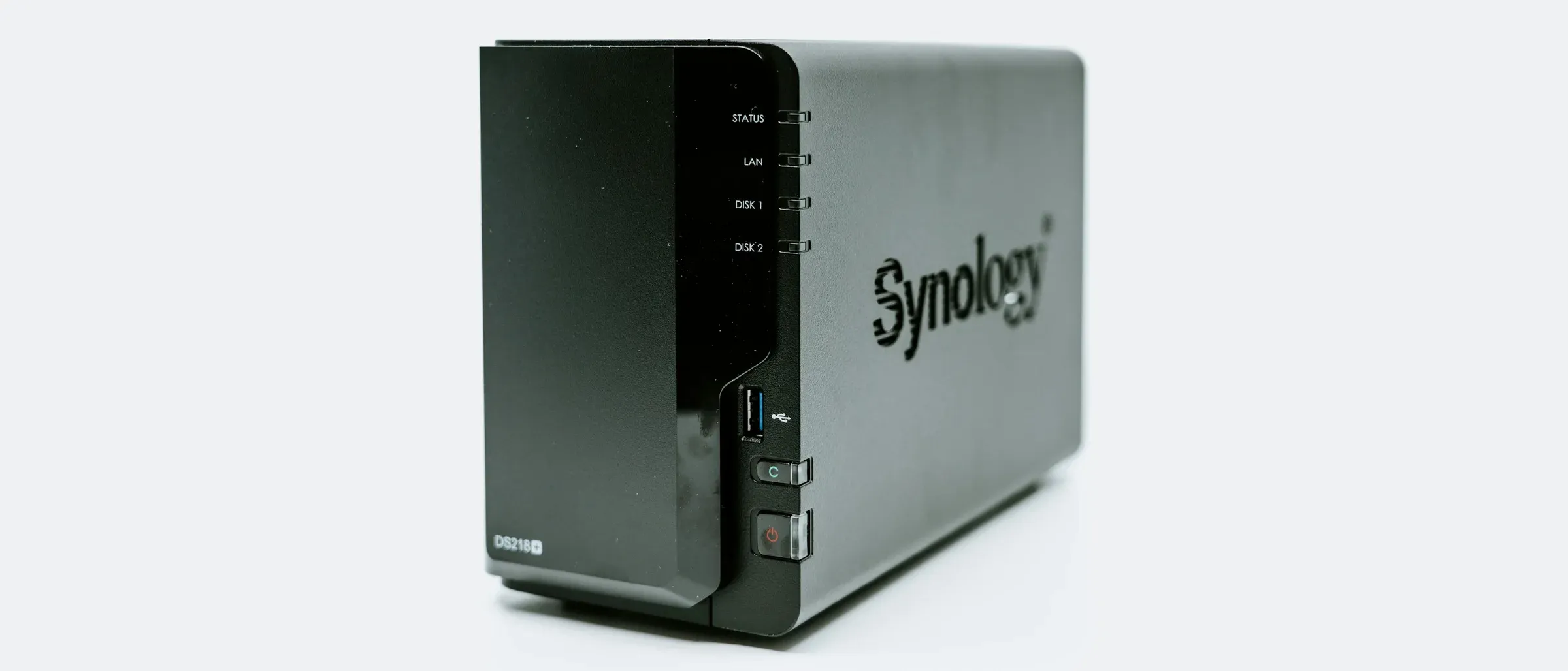A Synology NAS with two drive bays, seen at an angle against a light background