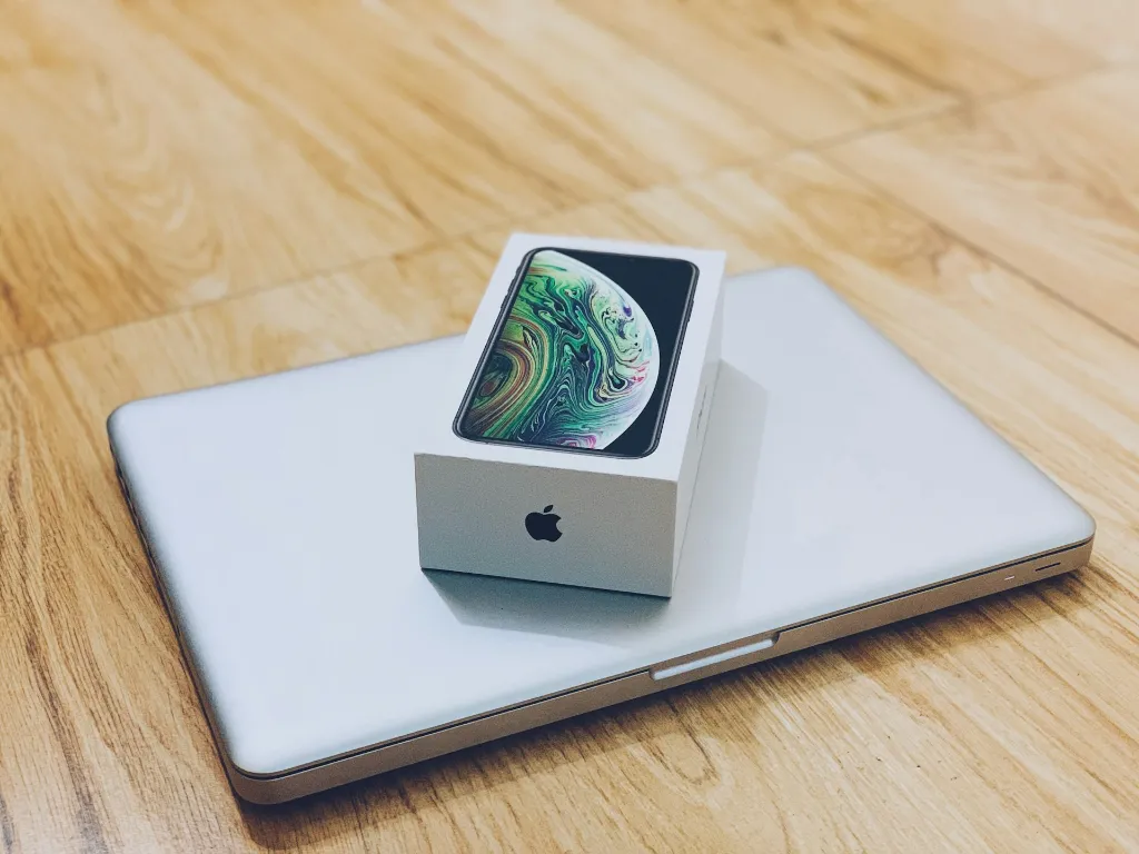 iPhone box on a silver MacBook on a wooden table