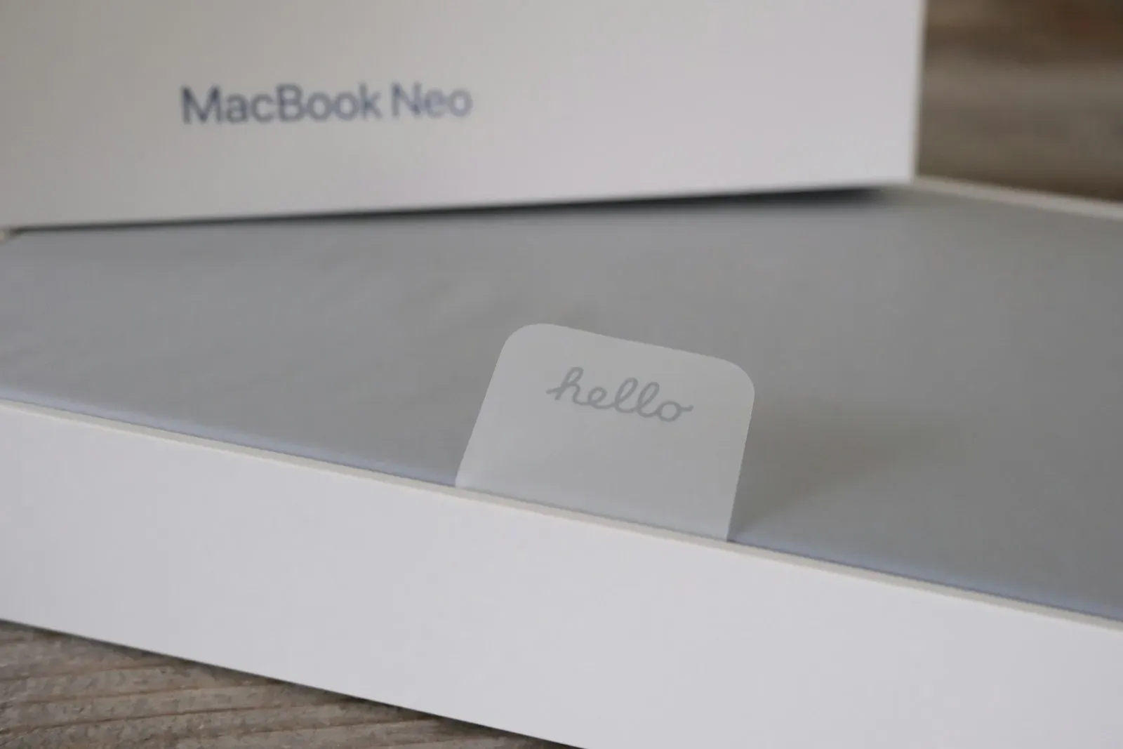 Een nieuwe MacBook in zijn doos, met het lipje hello op de beschermfolie